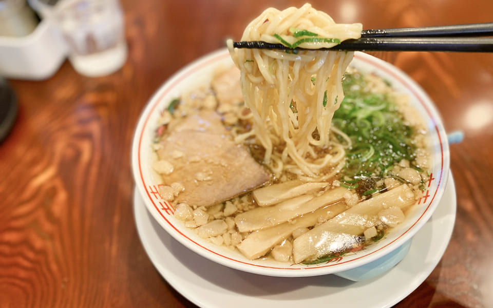 写真:ラーメンの麺を箸で持ち上げています