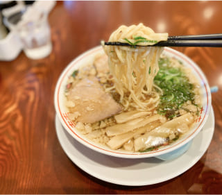 写真:ラーメンの麺を箸で持ち上げています