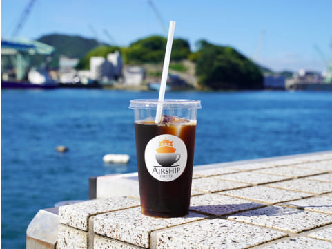 写真:海を背景にアイスコーヒーのカップが置いてあります